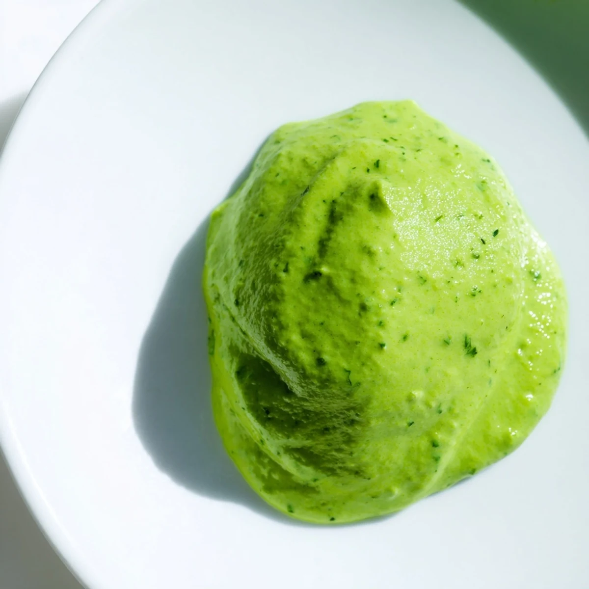 Smooth Peruvian green sauce aji verde served in rustic ceramic bowl with lime wedge