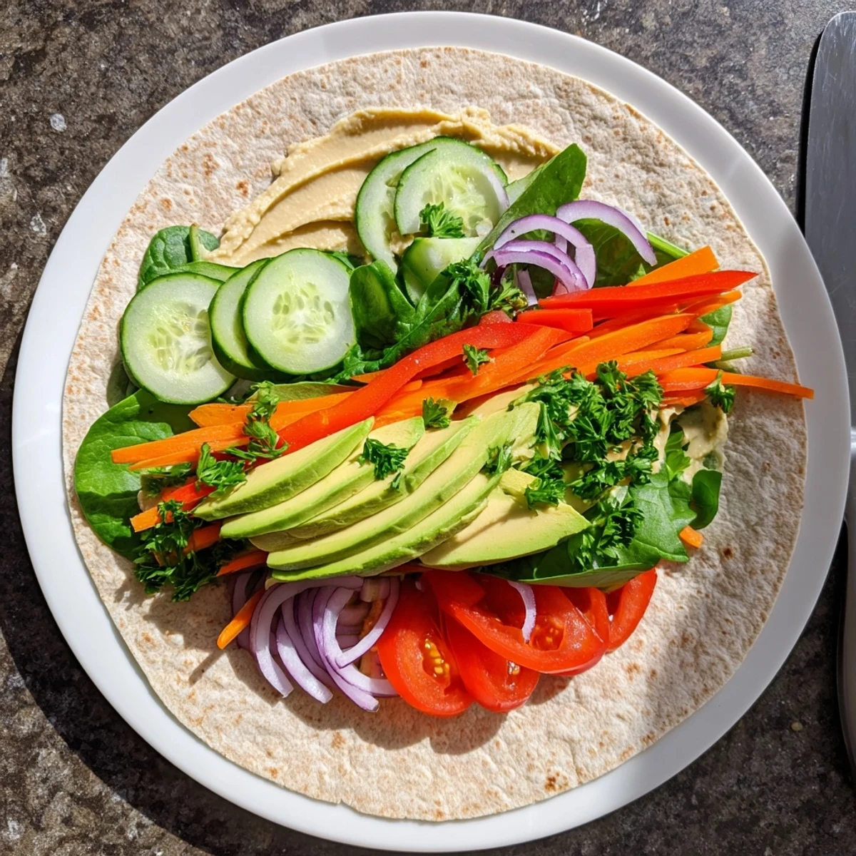 Golden sliced wrap revealing colorful layers of fresh vegetables and creamy hummus filling