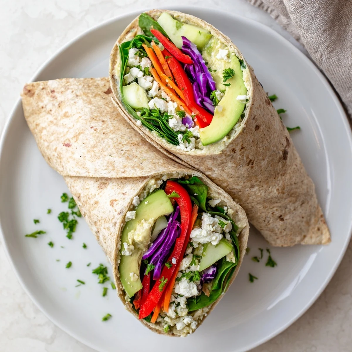 Mediterranean hummus veggie wrap sliced diagonally revealing vibrant layers of spinach bell peppers and cucumber