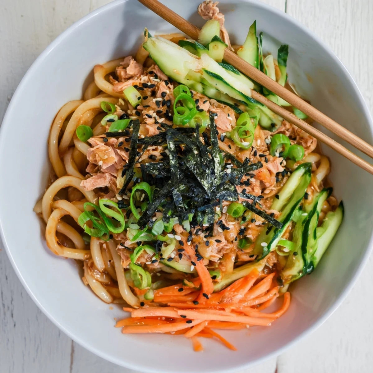 Spicy Tuna Udon noodles topped with sesame seeds and nori in a bowl