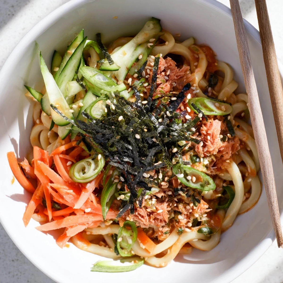 Japanese-style spicy tuna udon served with chili slices and toasted sesame topping