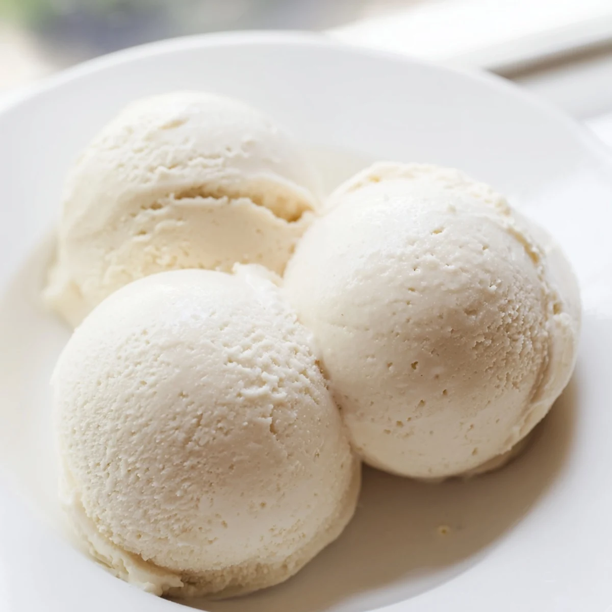 Creamy homemade vanilla ice cream scooped into a chilled glass bowl with fresh waffle cone