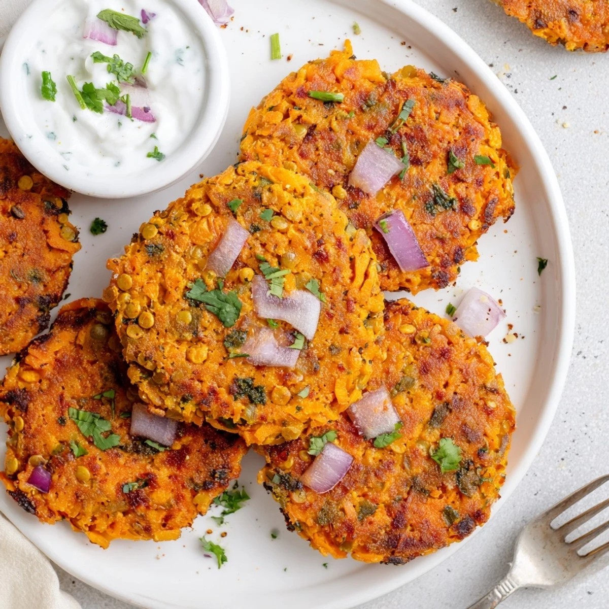 Crispy Sweet Potato Lentil Patties sizzling golden in skillet, served with yogurt.