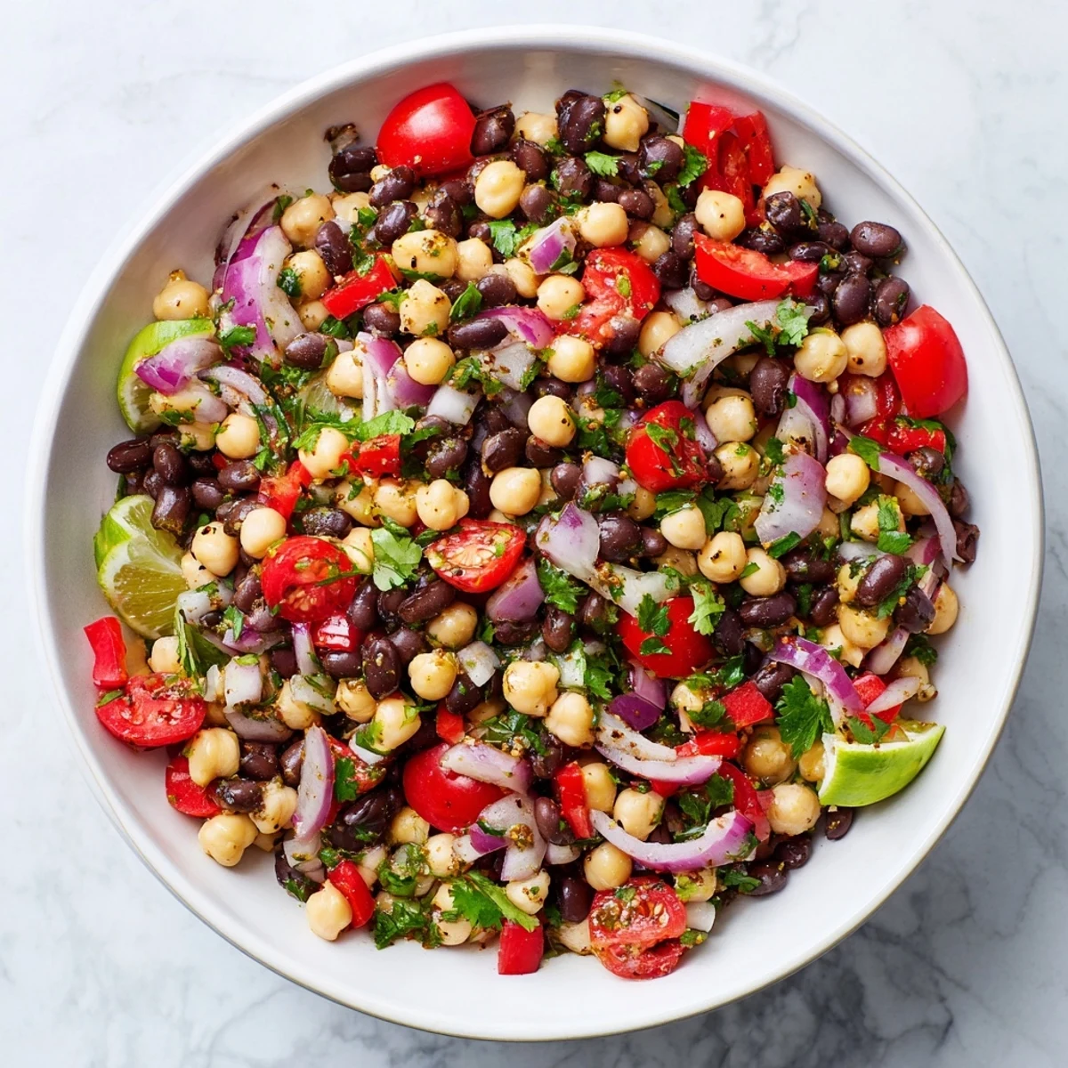 Colorful marinated cilantro lime bean salad with fresh vegetables in a white serving bowl