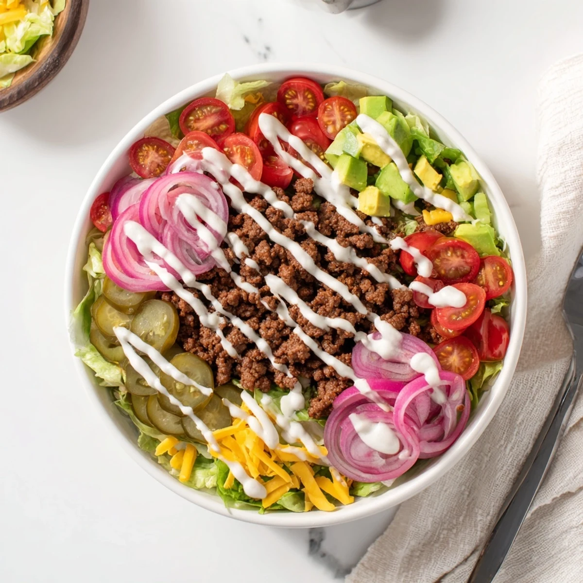 Colorful meal prep bowl featuring protein packed burger bowls with lettuce, tomatoes, cheese, pickles, and creamy dressing