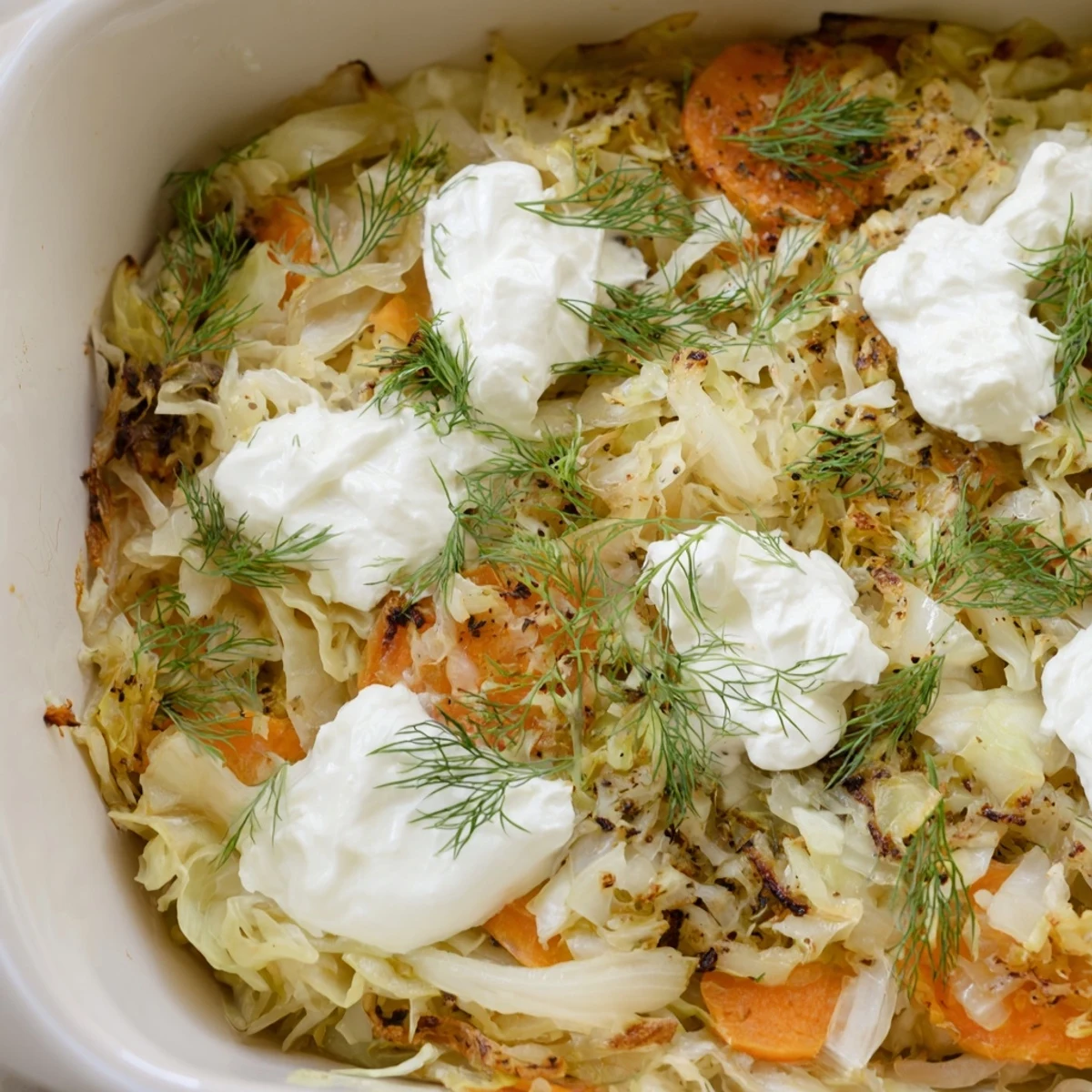 Golden brown slow roasted cabbage and sauerkraut casserole topped with fresh dill garnish