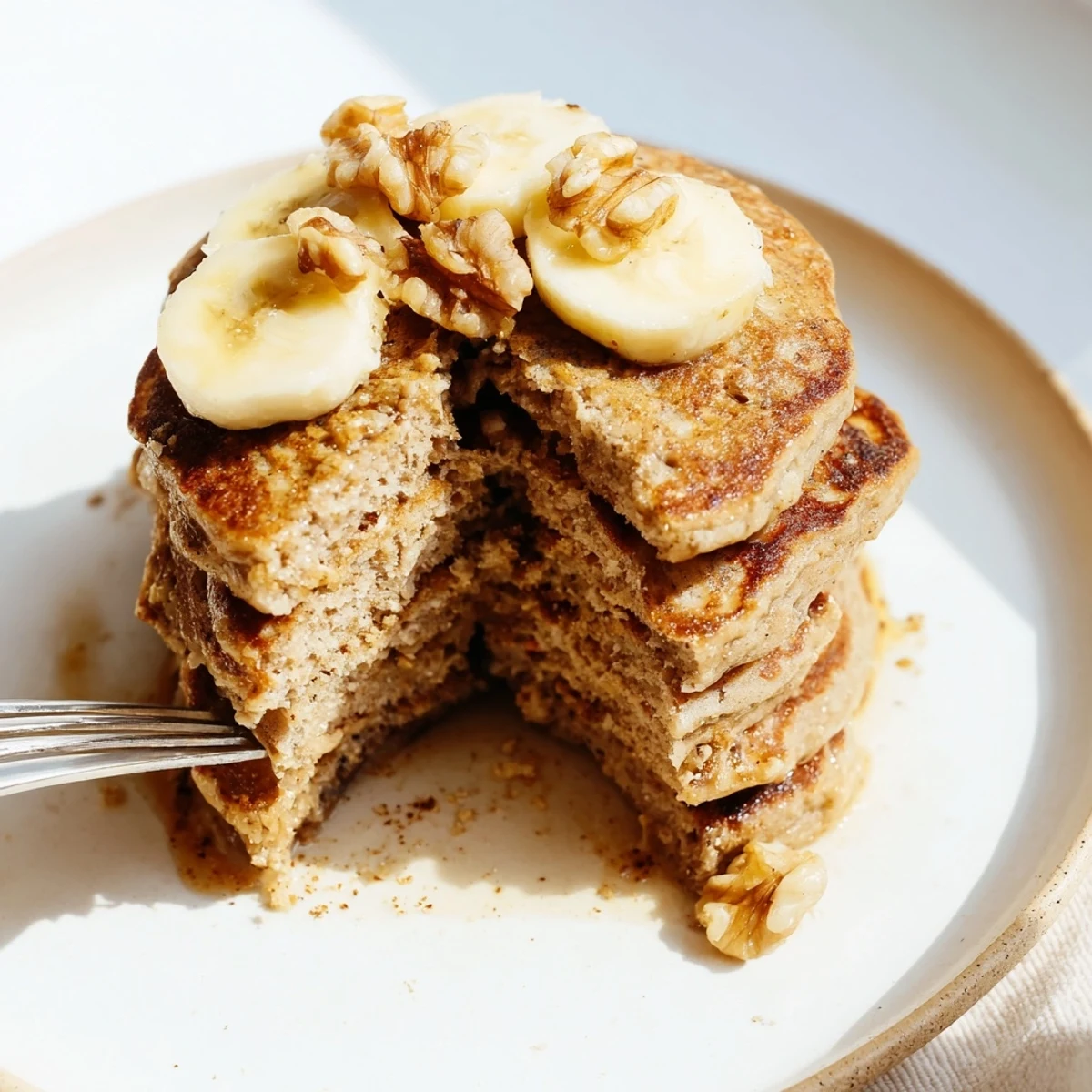 Fluffy protein banana pancakes cooking in a skillet with golden brown edges and steam rising