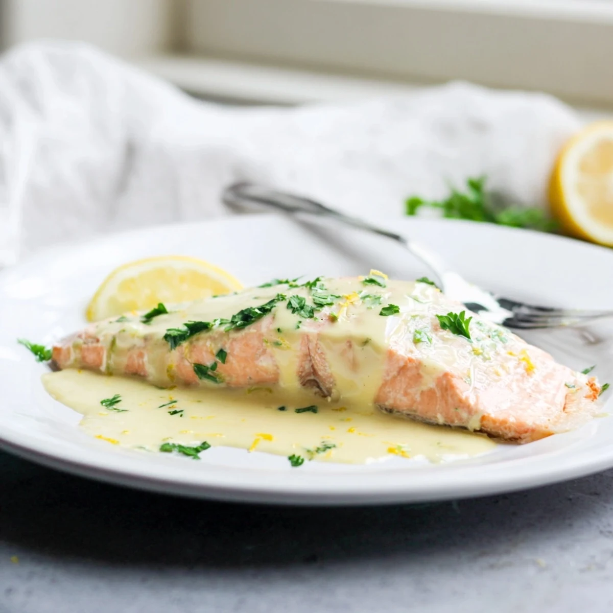 Golden pan-seared salmon fillet drizzled with rich lemon cream sauce and fresh parsley