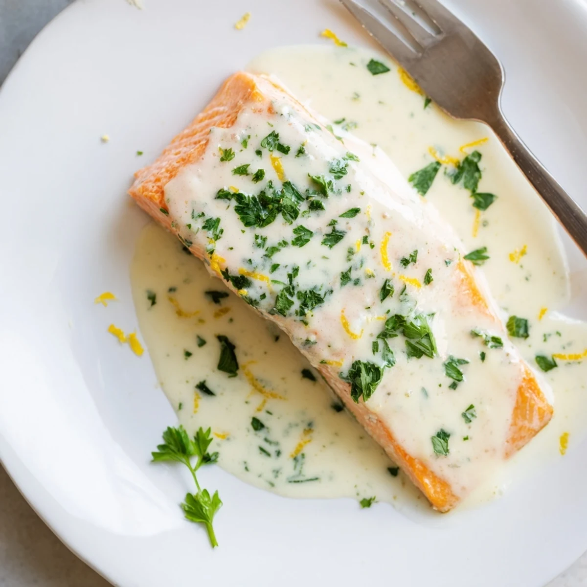 Succulent baked salmon fillet topped with zesty lemon cream sauce and chopped fresh herbs