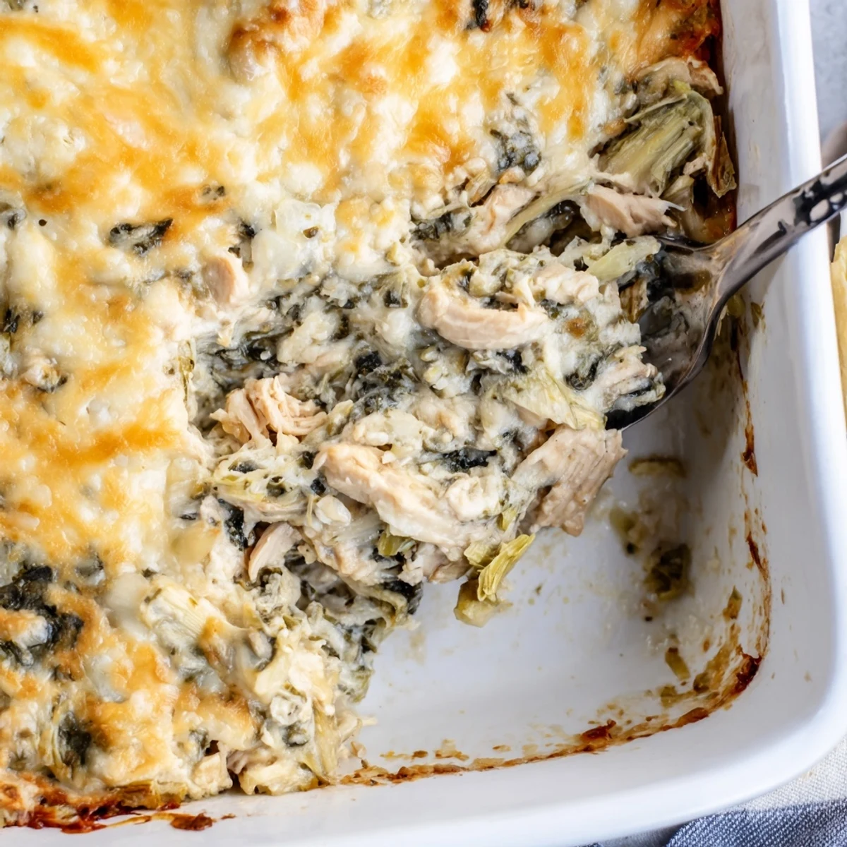 Hearty spinach artichoke chicken casserole featuring tender chicken pieces in a rich cheesy sauce