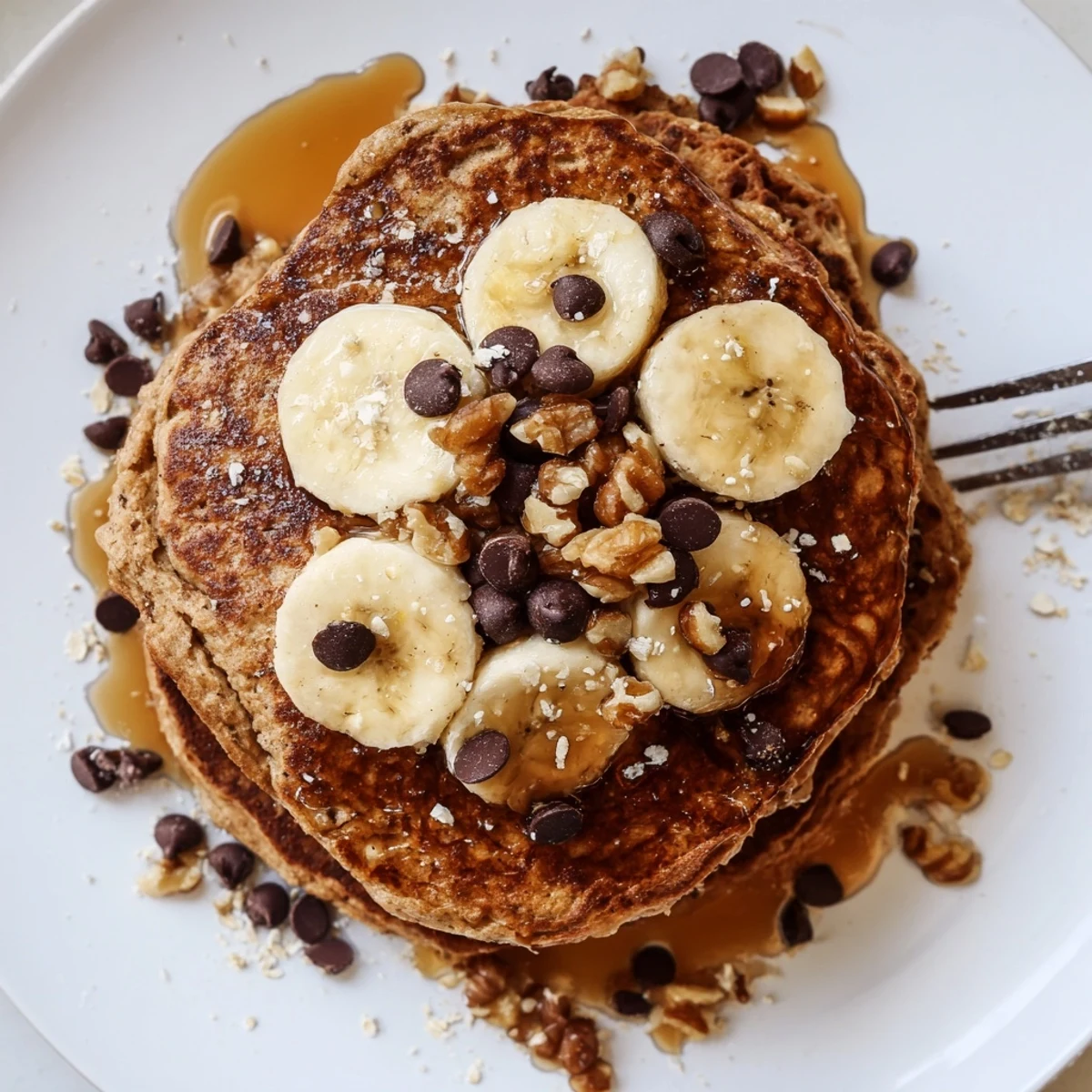 Protein Banana Pancakes stacked with golden edges, sliced bananas and maple drizzle