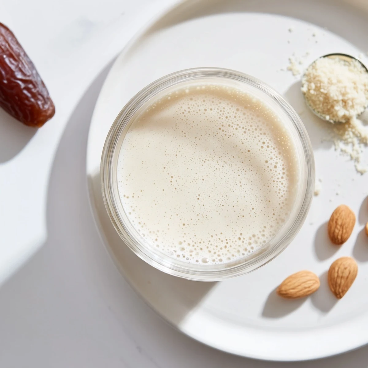 Homemade Almond Milk beside blender and soaked almonds on countertop  