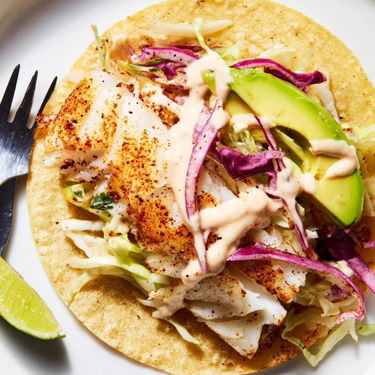 Bright slaw and avocado top Baked Cod Fish Tacos with Creamy Cilantro Lime Sauce.