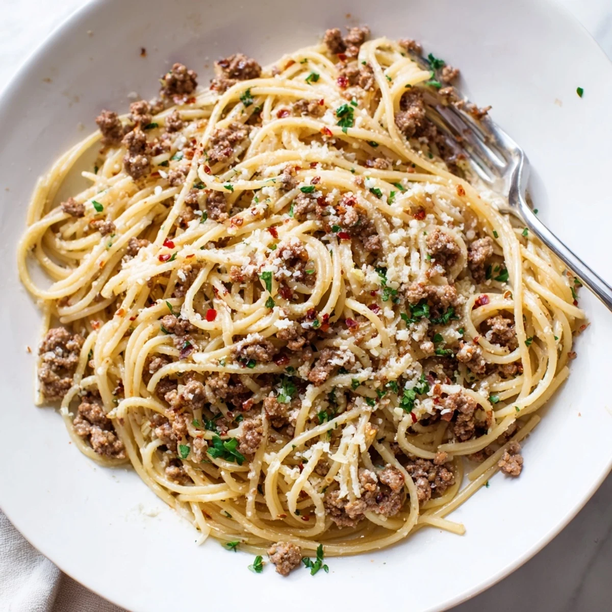 Steaming bowl of garlic butter pasta with ground beef coated in rich sauce
