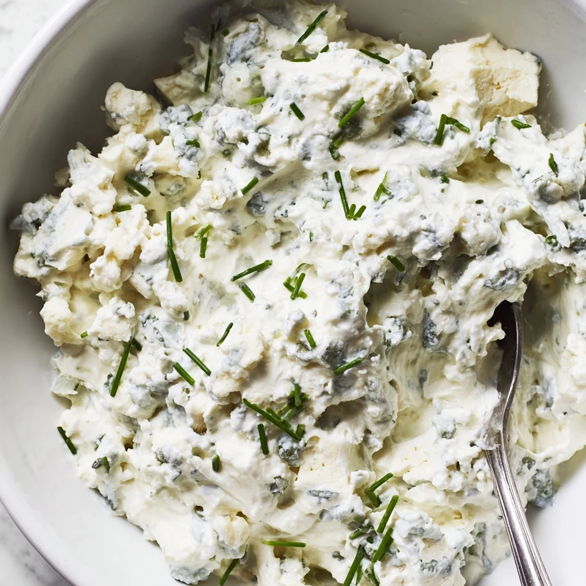 Creamy blue cheese dip served in a rustic bowl with fresh celery and carrot sticks