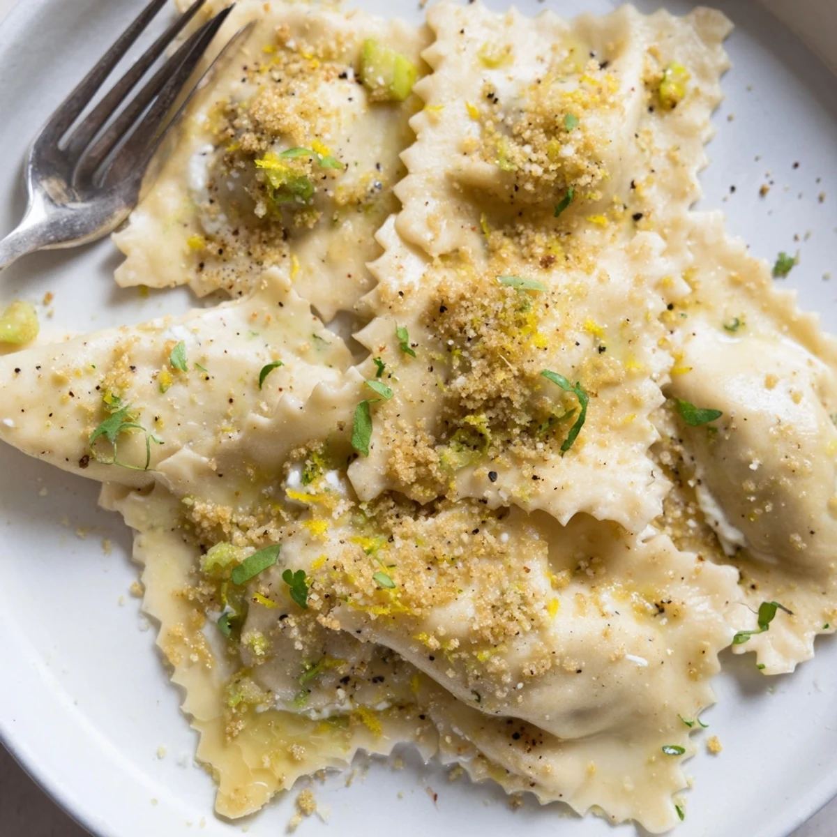 Homemade leek burrata triangoli glistening in lemon butter sauce topped with toasted sourdough crumbs