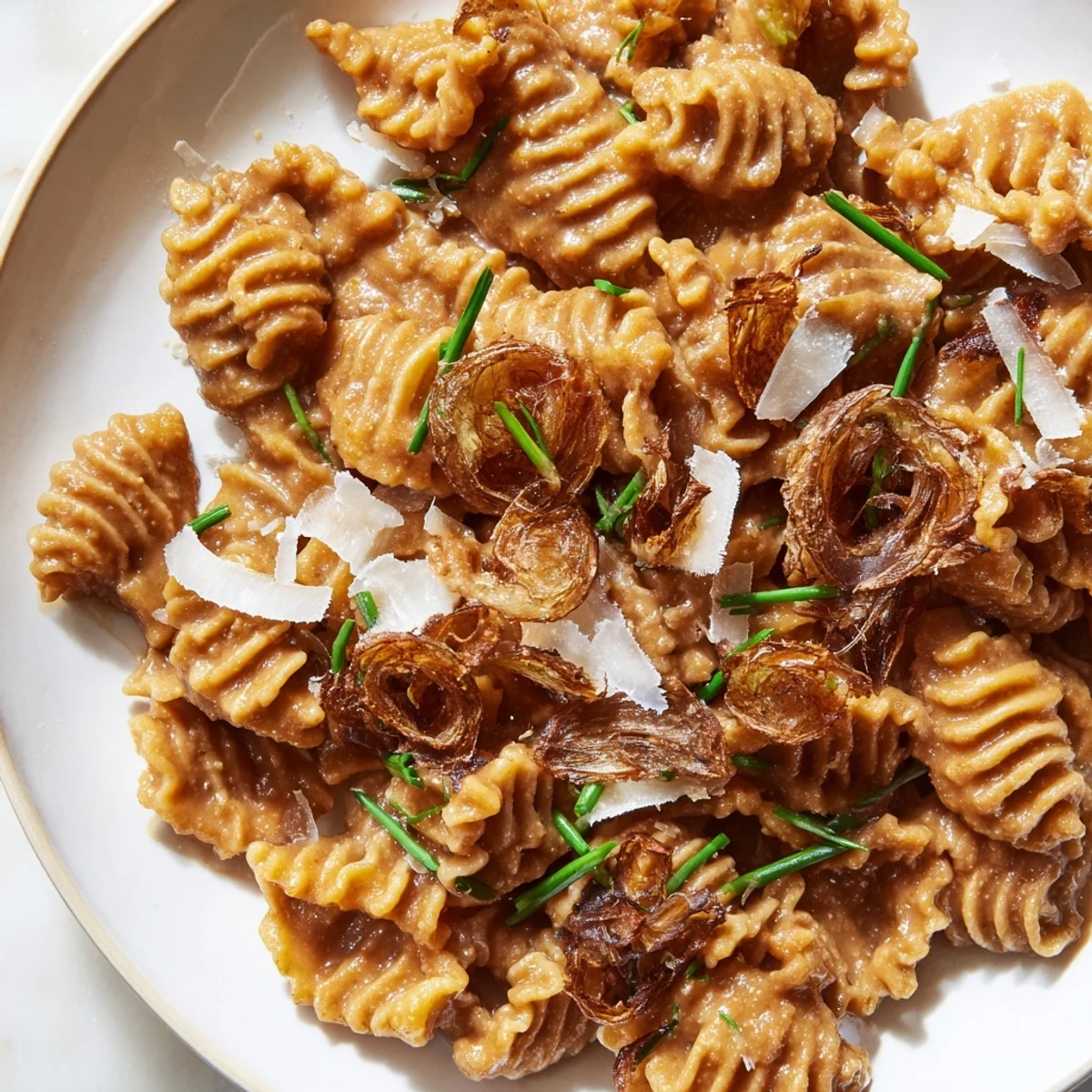 Golden brown butter miso roasted garlic radiatori topped with crunchy crispy shallots and Parmesan