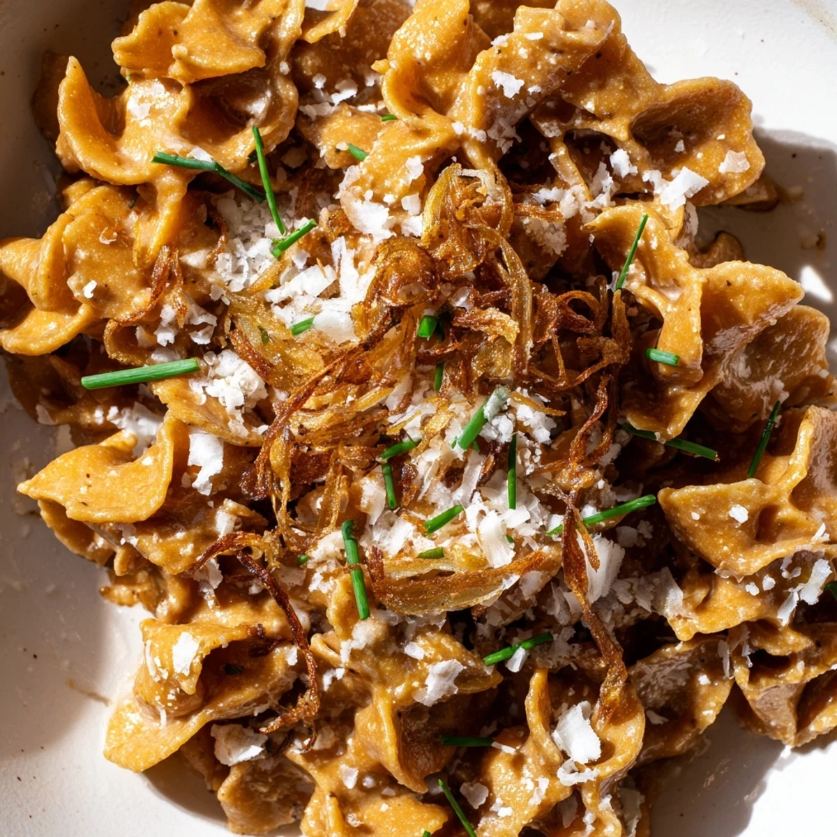 Steaming bowl of brown butter miso roasted garlic radiatori glistening with savory umami sauce