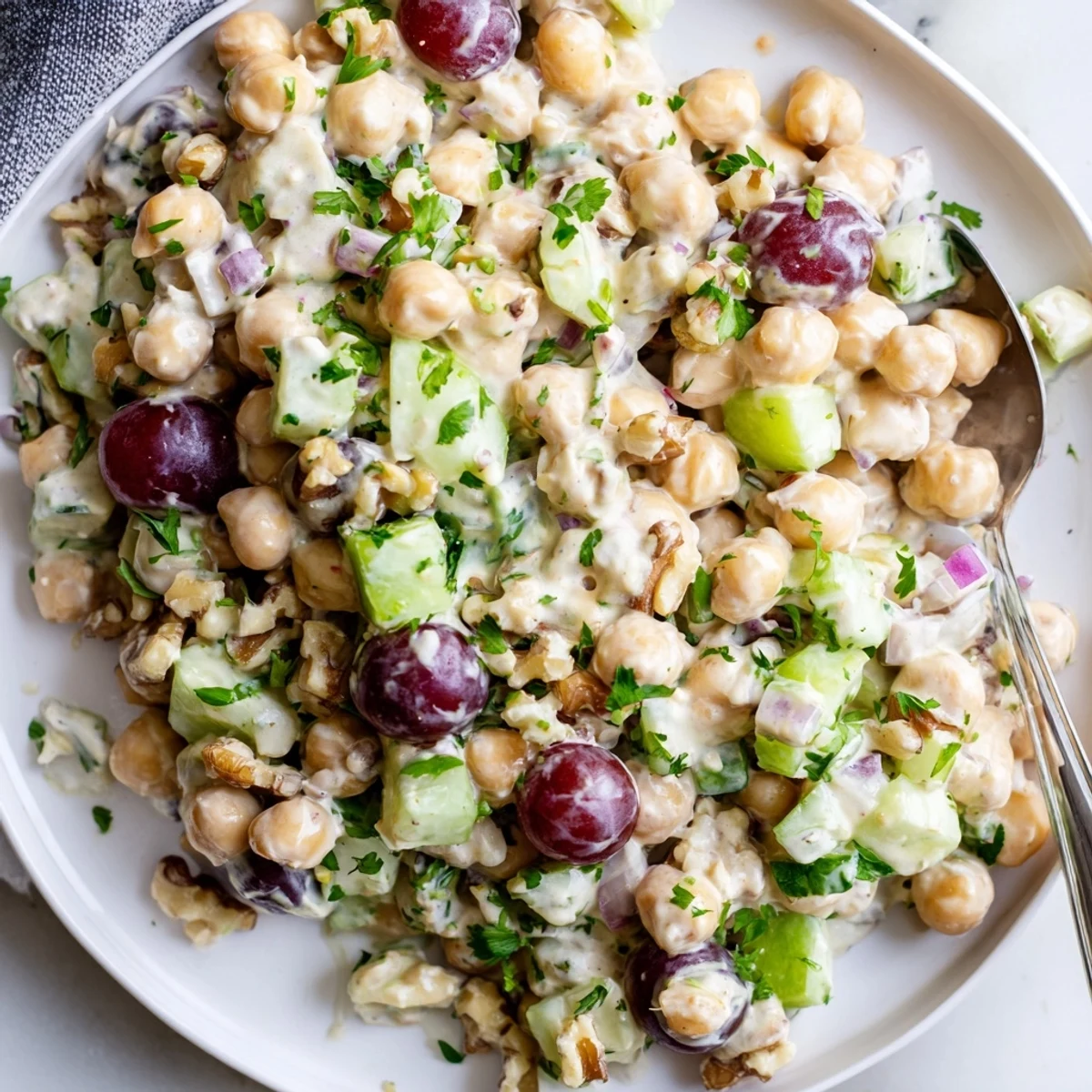 Vibrant vegan chicken salad scooped into a bowl beside fresh celery and grapes