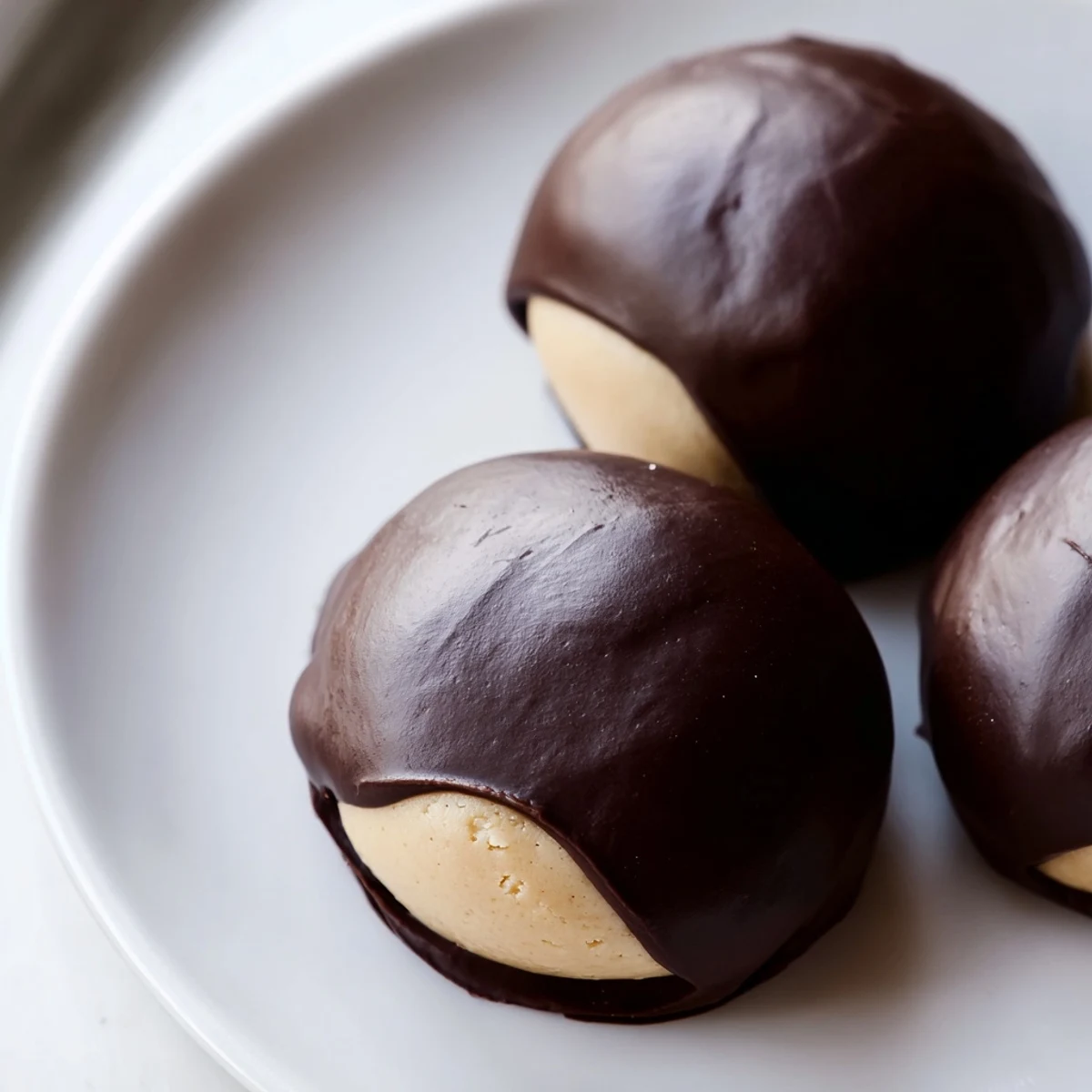 Buckeye Cookies with glossy chocolate dipping and creamy peanut butter centers on parchment