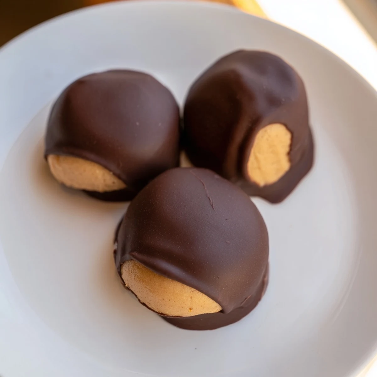 Hand holding a Buckeye Cookie showing the exposed peanut butter top dipped in chocolate