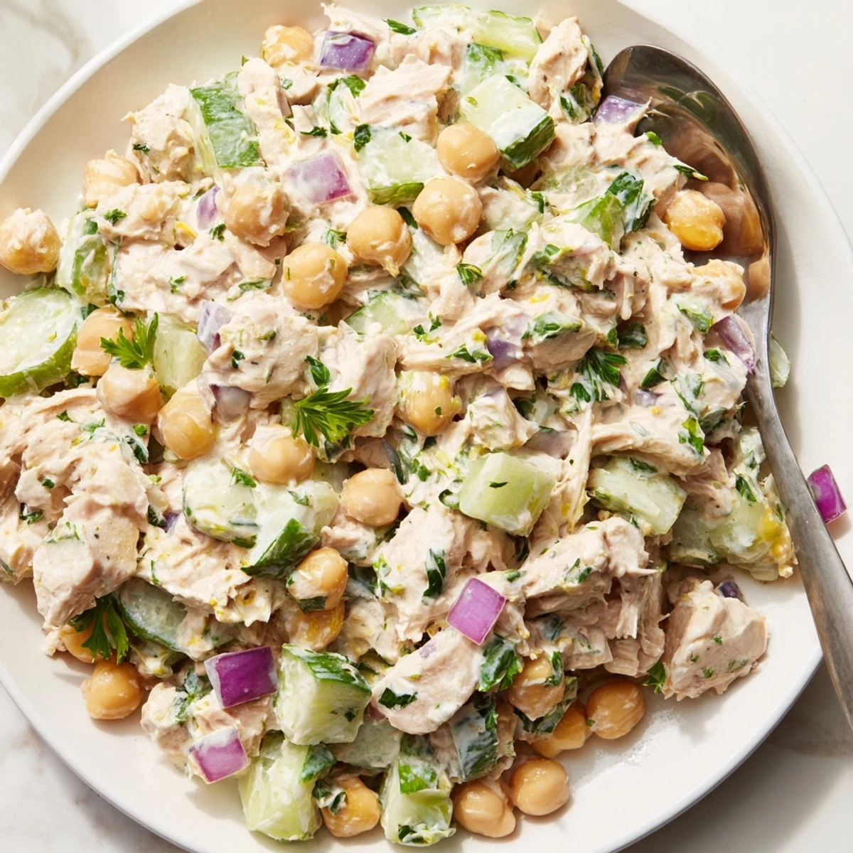 Creamy tuna chickpea cucumber salad served in a rustic bowl with fresh parsley
