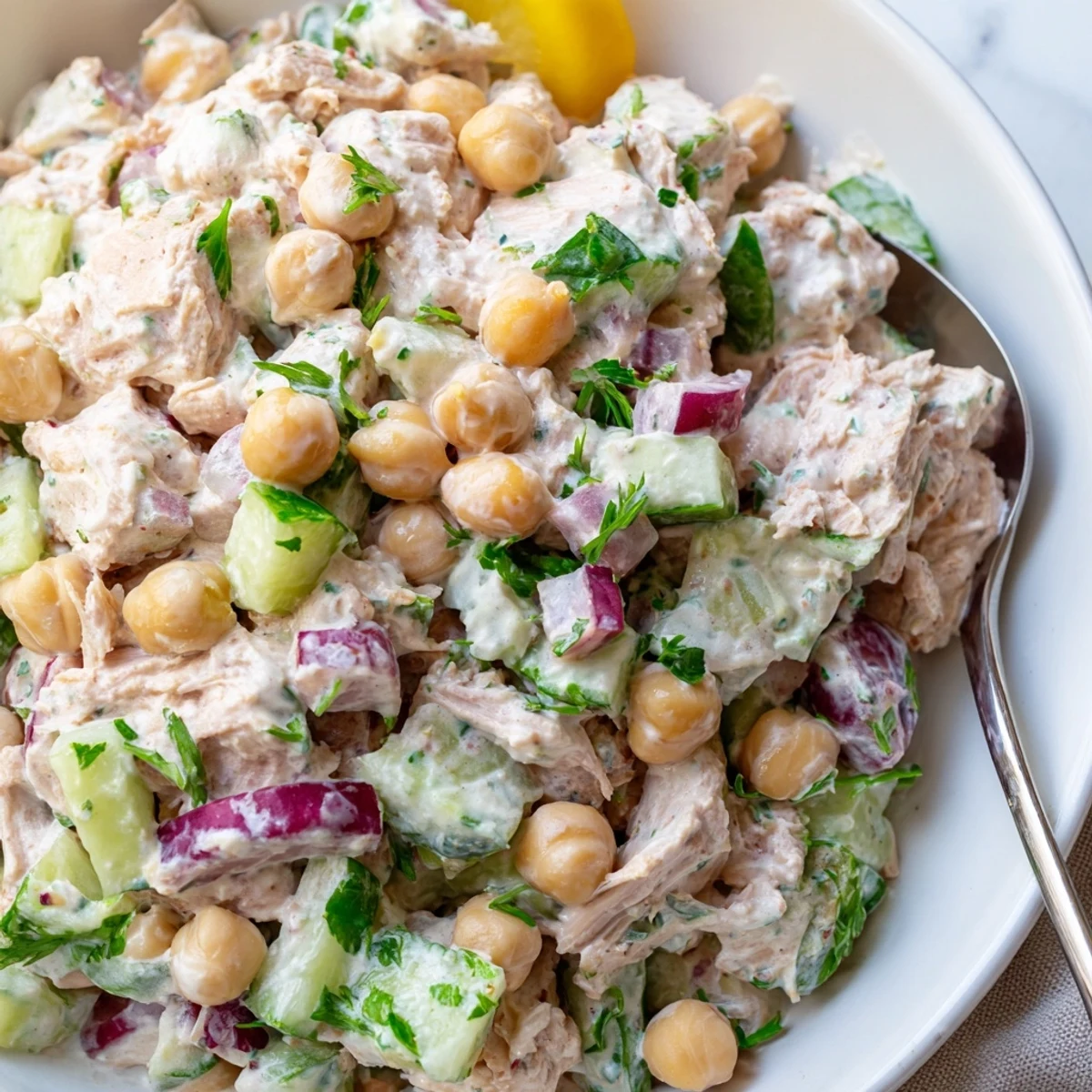Spoonful of creamy tuna chickpea cucumber salad with diced vegetables and tangy dressing