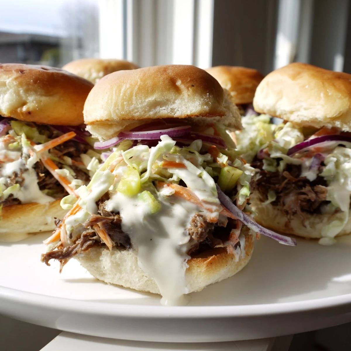 Juicy Alabama white sauce pulled lamb sliders drizzled with creamy sauce and pickled onions