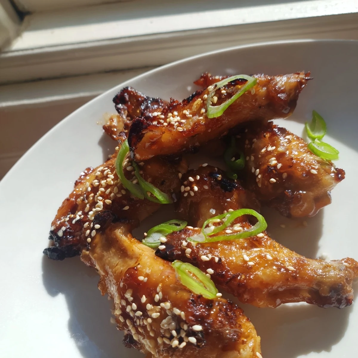 Golden sticky miso honey marinated chicken wings fresh from the oven topped with sliced green onions