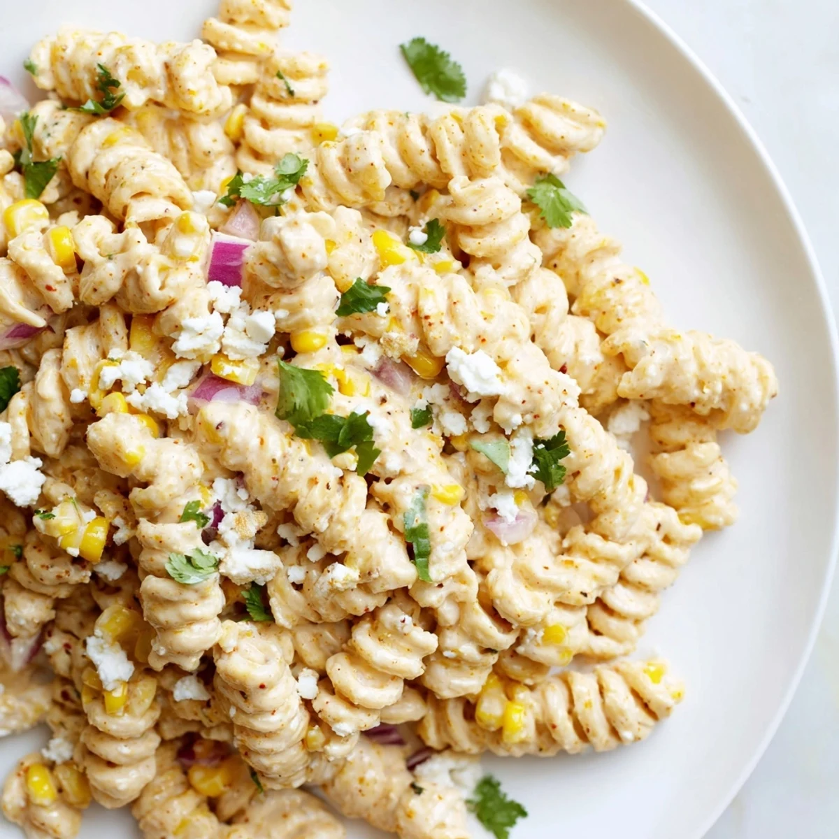 Creamy elote pasta salad topped with crumbled cotija cheese and fresh cilantro