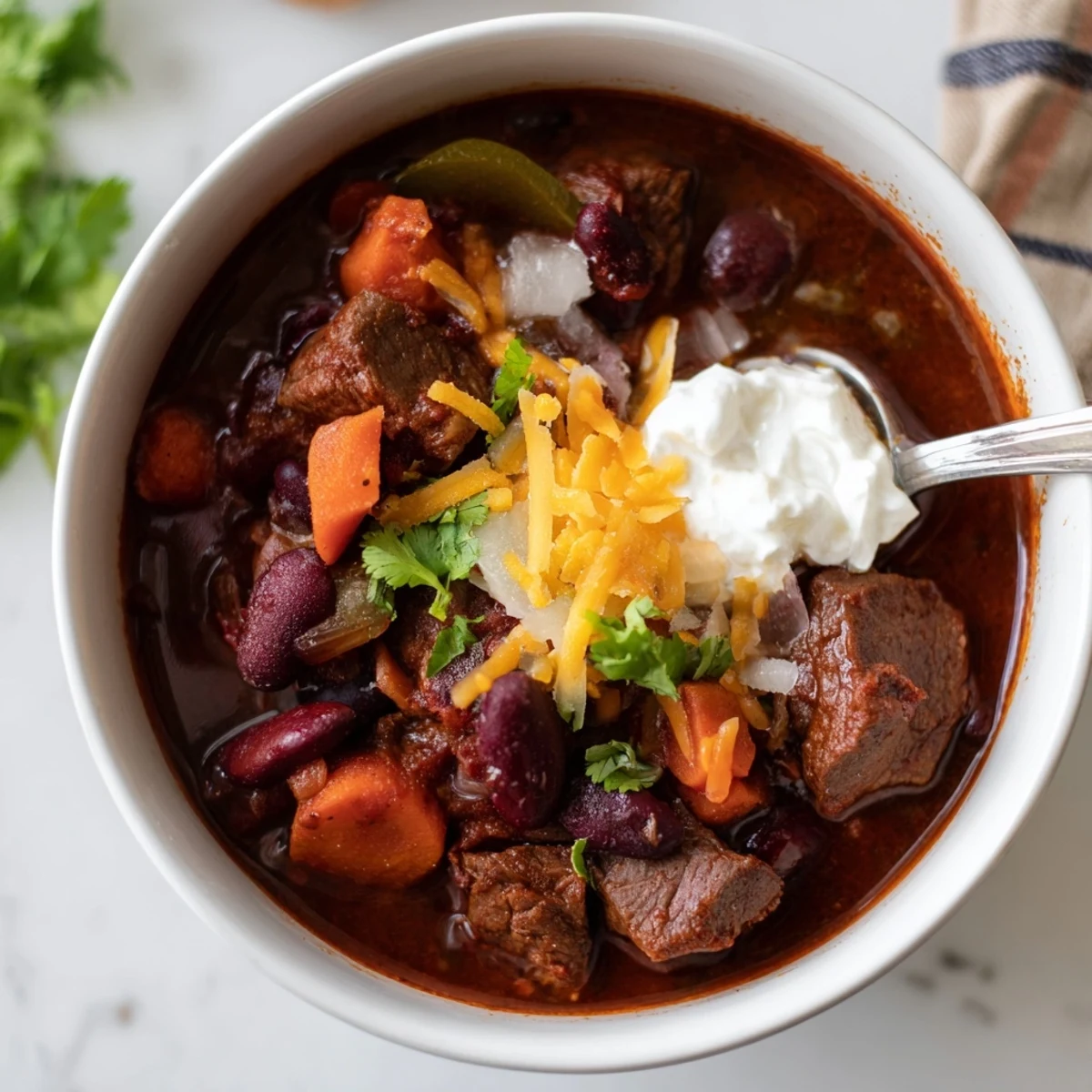 Hearty beefy chili stew loaded with tender beef chunks beans and vegetables in spicy sauce