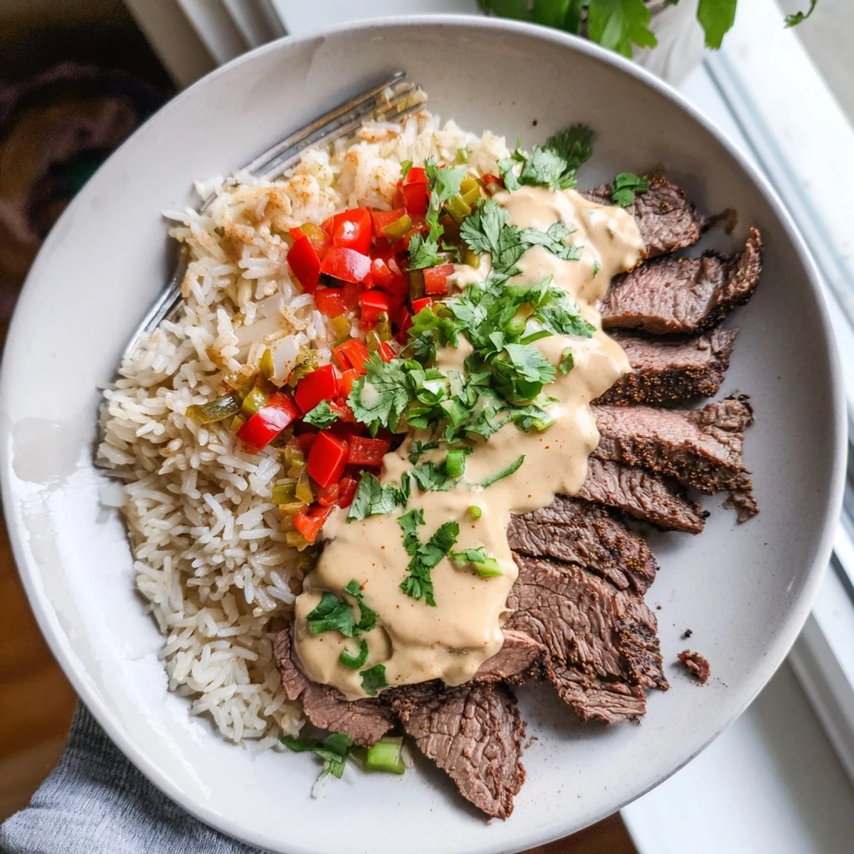 Sizzling steak queso rice in a cast iron skillet with colorful bell peppers
