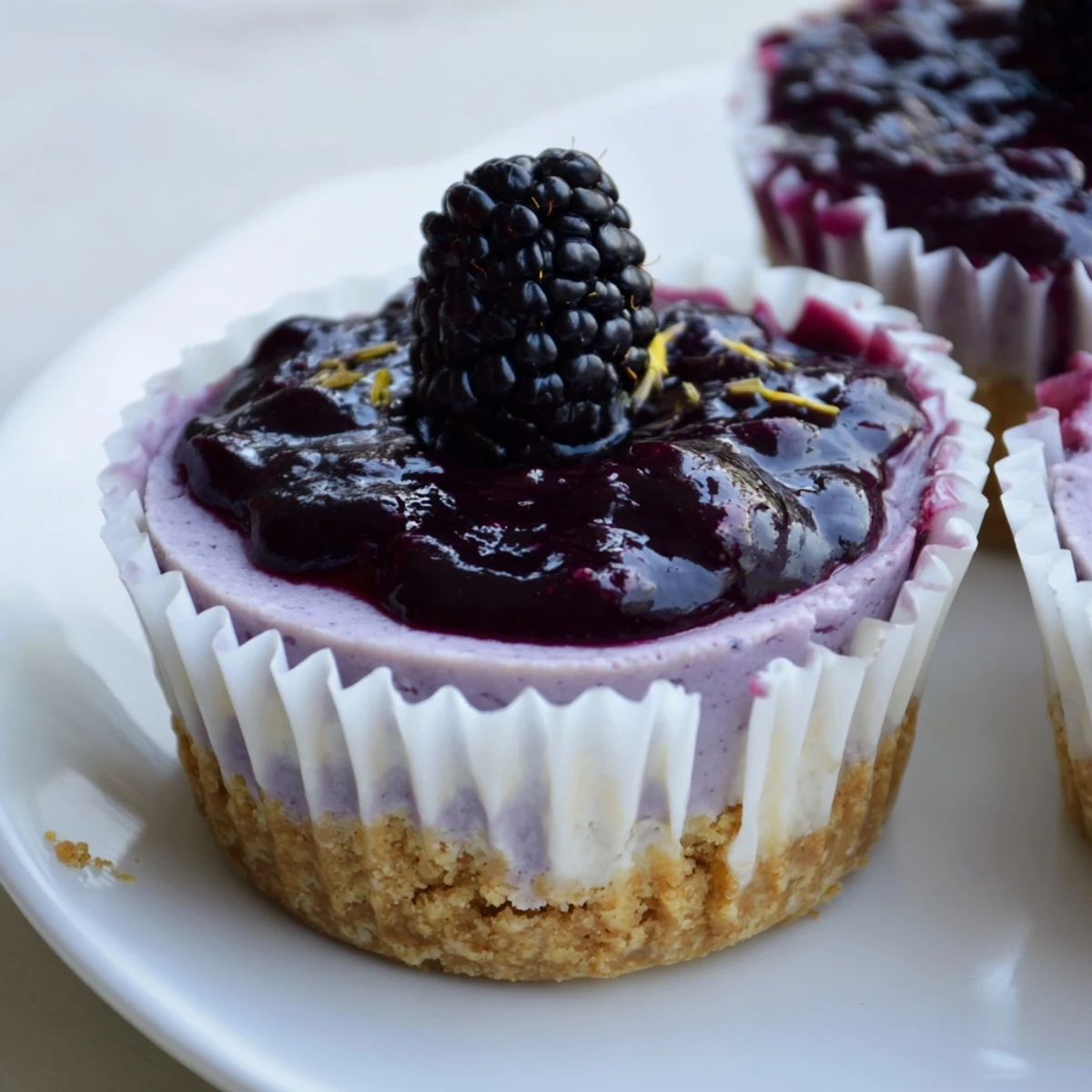Individual creamy no bake mini blackberry lavender cheesecakes garnished with fresh berries and delicate lavender sprigs