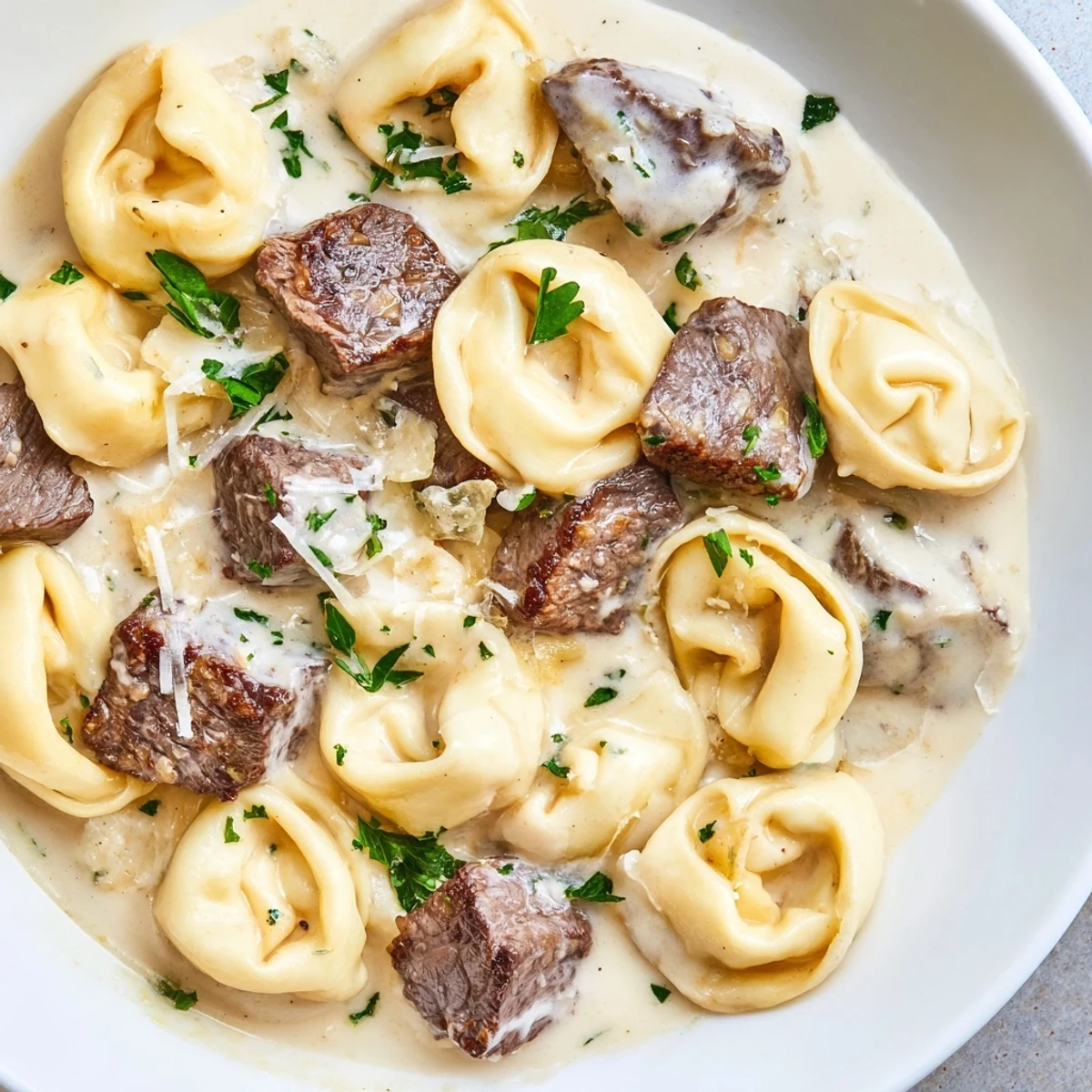 Creamy garlic steak tortellini in a golden parmesan sauce with fresh parsley