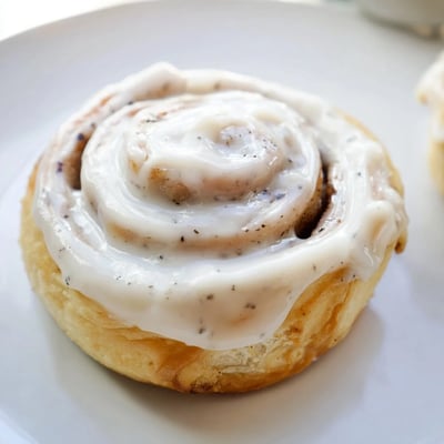 Freshly baked Keto Cinnamon Buns showcasing a golden swirl of cinnamon and soft almond flour texture on a white plate.