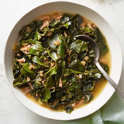 Golden green collard greens dish served in bowl alongside savory cornbread for Southern comfort meal