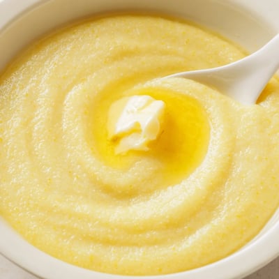 Golden maize porridge simmering in a saucepan, smooth and thick with steam rising