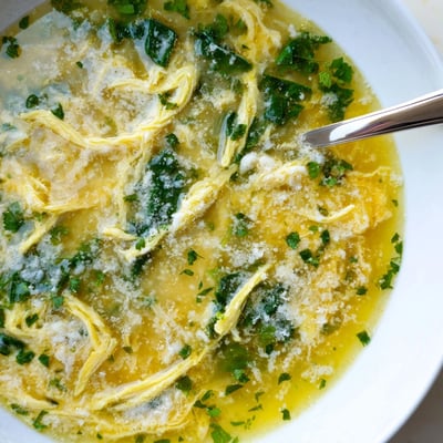 Stracciatella Soup topped with grated Parmesan in a golden savory chicken broth