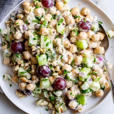 Vibrant vegan chicken salad scooped into a bowl beside fresh celery and grapes
